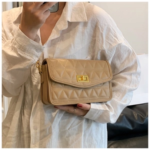 Détail du sac bandoulière matelassé beige avec fermoir rotatif doré et chaîne en métal