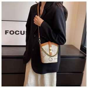 Detailed view of cream mini bucket bag featuring black MG logo and gold chain strap