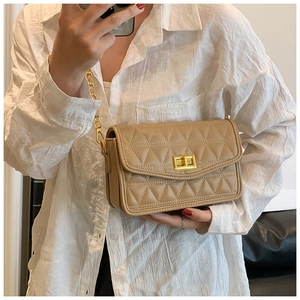 Détail du sac beige matelassé avec bandoulière en chaîne dorée et fermoir rotatif