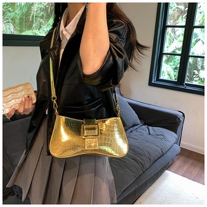Detail of gold faux crocodile underarm bag with square buckle on a model in leather jacket
