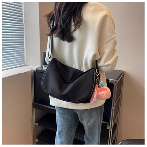 Detailed back view of a black nylon crescent saddle bag with peach plush charm