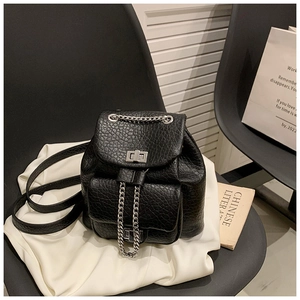 Detalle de una mini mochila negra de piel con patrón de lichi y cierres metálicos plateados