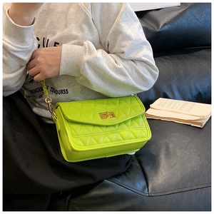 Détail du petit sac bandoulière matelassé vert fluo avec chaîne dorée sur canapé