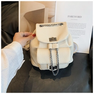 Detalle de la mochila crema con cadenas, cierres giratorios plateados y textura
