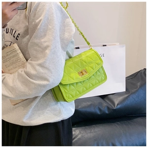 Détail d'un sac bandoulière matelassé vert vif avec chaîne dorée et fermoir métal