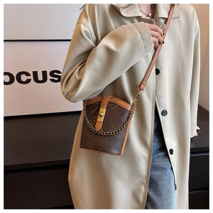 Detailed view of a vintage bucket bag featuring a gold turn-lock and leather chain strap