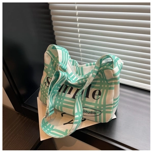 Detail of the green plaid canvas pillow bag with Simple print and wide shoulder strap