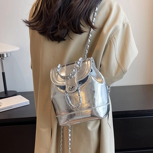 Silver metallic mini chain backpack with glossy finish styled on a tan trench coat