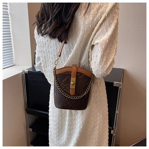 Detail of a brown monogram bucket bag with gold chain strap and vintage twist-lock closure