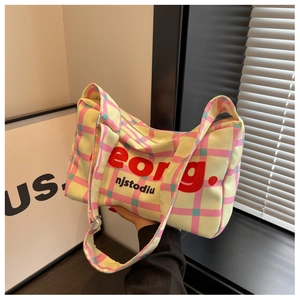 Detail of colorful checkered canvas pillow bag with bold typography and secure zipper