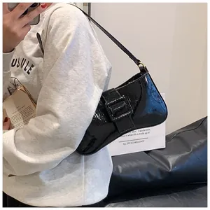 Detail of black crocodile texture baguette bag with oversized square buckle on shoulder