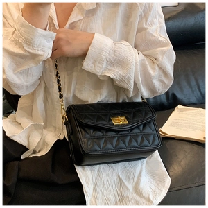 Détail d'un sac à bandoulière en cuir matelassé noir avec fermoir doré et chaîne
