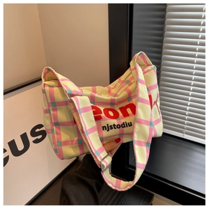 Detailed shot of canvas shoulder bag featuring plaid patterns and bold logo print