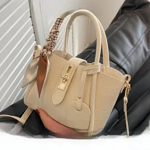 Détail du sac fourre-tout crème avec texture litchi, fermoir doré et foulard en soie