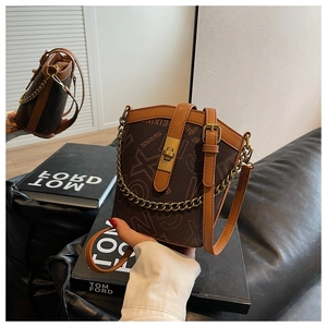 Close-up of vintage brown patterned bucket bag with gold twist lock and chain strap
