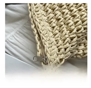 Detailed close-up of smooth metal zipper and woven texture on straw tote bag