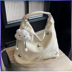 Détail d'un sac cabas plissé blanc avec papillons argentés et pendentif nuage en peluche
