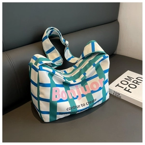 Detail of blue-green plaid canvas shoulder bag featuring Bonjour print and wide strap