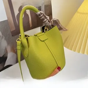 Détail du sac seau jaune en cuir grainé avec poignée ornée d'un foulard en soie