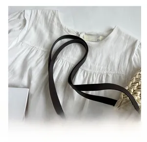 Detail view of comfortable black synthetic leather shoulder strap on a white fabric bag