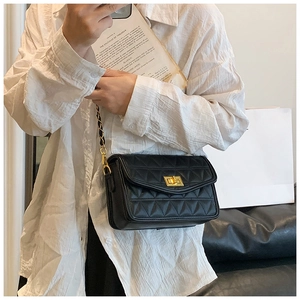 Détail du sac bandoulière matelassé noir avec chaîne dorée et fermoir pivotant en métal
