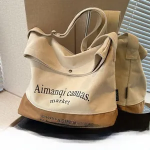 Détail du sac cabas en toile montrant la texture beige et le fond en cuir marron