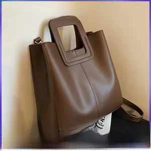 Vue détaillée du sac cabas marron foncé avec poignées découpées et texture synthétique lisse