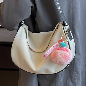 Minimalist cream crescent saddle bag with black logo wide strap and plush pendant