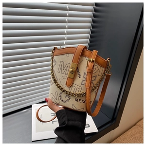 Detail of cream bucket bag featuring black letter print and vintage gold metal turn-lock
