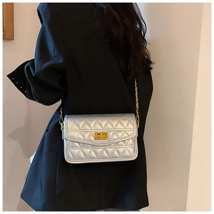 Détail du sac matelassé argenté avec fermoir doré porté sur une veste de tailleur