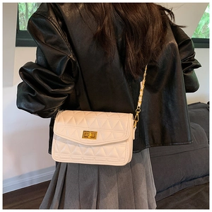 Sac bandoulière matelassé avec chaîne dorée et fermoir pivotant sur veste en cuir noir