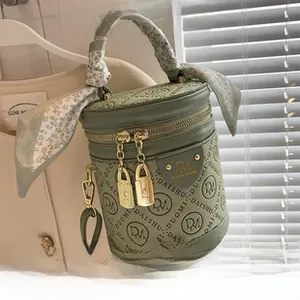 Détail du sac seau vert sauge avec logo DM gaufré et poignée en foulard de soie floral