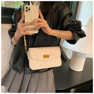 Détail du sac bandoulière matelassé crème avec chaîne dorée et fermoir sur un mannequin