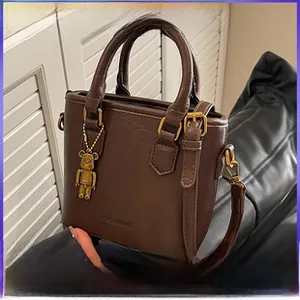 Vue détaillée du sac cabas en cuir grainé marron foncé avec un charm ours doré