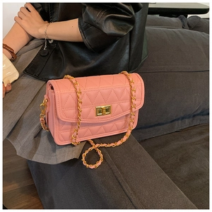 Détail d'un sac bandoulière rose matelassé avec chaîne dorée et fermoir rotatif en métal