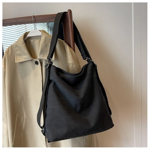 Detail of black canvas tote bag with adjustable shoulder strap and silver metal buckle