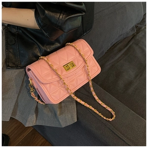 Détail du sac à bandoulière matelassé rose avec chaîne dorée sur la tenue
