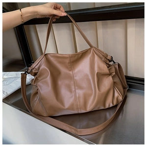 Detail of brown leather tote bag with lychee texture and adjustable shoulder strap