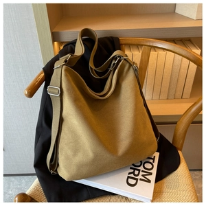 Detail of khaki canvas hobo bag with adjustable wide shoulder strap on wooden chair