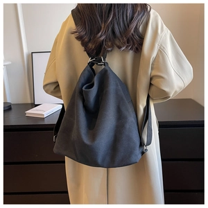 Close-up of black canvas backpack with drawstring closure and metallic ring detail