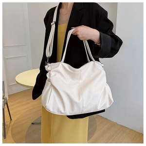 Detail of soft white PU leather tote bag with pleated design and dark metal hardware