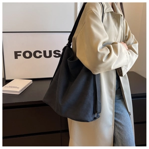 Detail of a black canvas tote bag showing the thick texture and wide shoulder strap