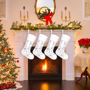 Set of four plush white Christmas stockings with silver snowflake embroidery on mantel