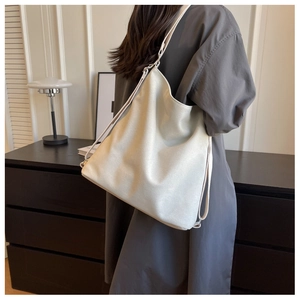 Side view of a minimalist large white canvas tote bag worn by a model in a modern home