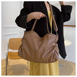 Detail of warm brown soft PU leather tote bag showing slouchy V-shape and side pleats