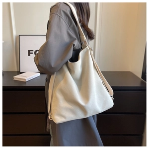 Detailed side view of off-white canvas tote bag on model in cozy home setting