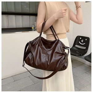 Outdoor shot of a dark brown leather tote bag with soft textures and shoulder strap