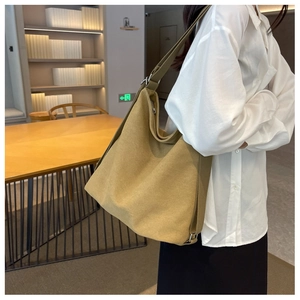 Detail of a large mustard canvas tote bag showing the texture and minimalist shoulder strap