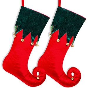 Detail of velvet Christmas elf stockings with curled toes and golden bells decor