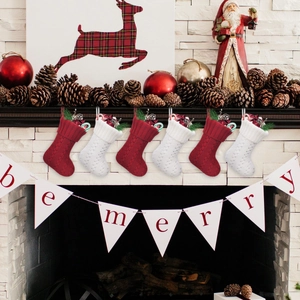 Set of 6 red and white knitted Christmas stockings with pine cones on fireplace